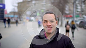 Young man asian smiling and looking at camera. Portrait of a happy handsome young man in a urban street. Close up face