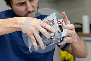 Young man assembles electronic computer components with his own hands. Hobby, technician, do-it-yourself assembly and invention