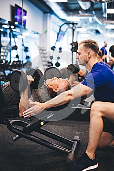 Young man assisting senior man at the gym.