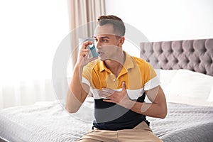 Young man with asthma inhaler on bed