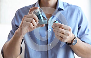 Young man with asthma inhaler indoors