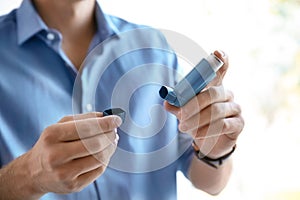 Young man with asthma inhaler indoors photo