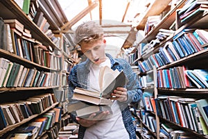 A young man with astonished emotions reads a book in a bright public library