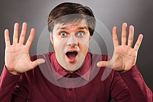 Young man with astonished expression and hands up