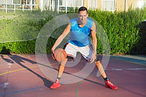 Young man athlete on basketball court dribbling