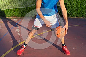 Young man athlete on basketball court dribbling