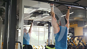 Young man athlete doing pull-up bar abdominal exercise in gym