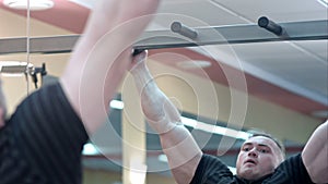 Young man athlete doing pull ups chin ups in the gym