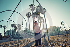 A young man athlete working out on traveling rings on muscle beach, Santa Monica, California