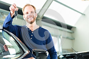 Young man with auto in car dealership