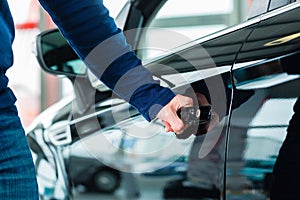 Young man with auto in car dealership