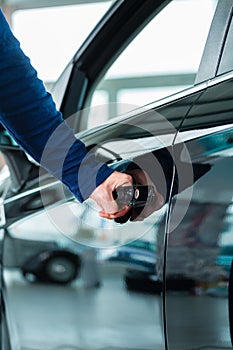 Young man with auto in car dealership