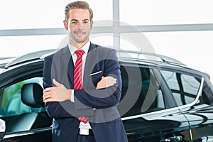 Young man or auto dealer in car dealership