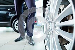 Young man or auto dealer in car dealership