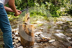 Young man with axe chopping wood on a chopping block