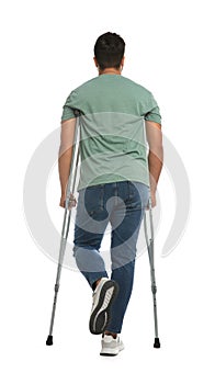 Young man with axillary crutches on white background, back view photo