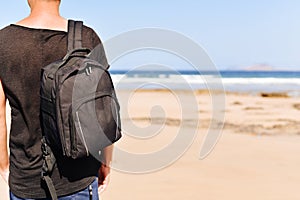 Young man with a backpack on the beach