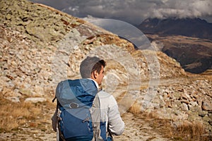 Young man with backpack hiking in the mountains. Hiking concept
