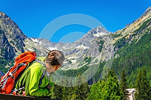 Young man with backpack looking at mountain peaks