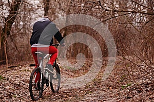 Young man with backpack riding bicycle on mountain road in the forest