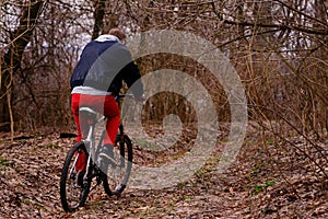 Young man with backpack riding bicycle on mountain road in the forest