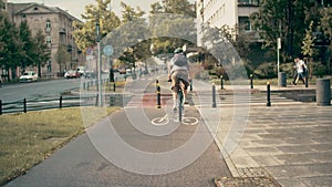 Young man with backpack riding his bicycle along urban bike path