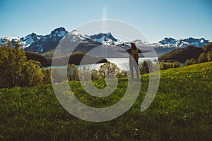 Young man with a backpack standing on the background of mountains and lake. Space for your text message or promotional content.