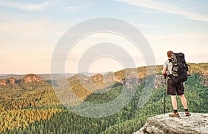 Young man with backpack standing on top of mountain and enjoying mountain view. Hiker on the mountain top. Sport and active life