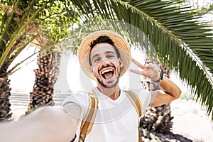 Young man with backpack taking selfie portrait on exotic beach -Smiling happy guy enjoying summer holidays