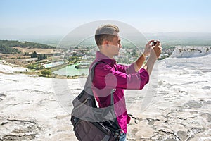 Young man with backpack, tourist, takes pictures with his mobile