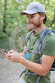 young man with backpack using smart phone on beautiful nature