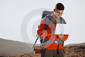 Young man backpacker using his laptop in mountain journey