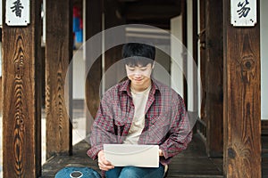 Young man backpacking in Korea. using a laptop sitting in a Korean traditional house.