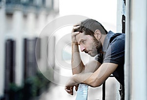 Young man at balcony in depression suffering emotional crisis and grief