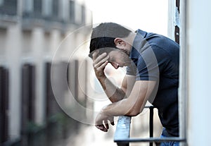 Young man at balcony in depression suffering emotional crisis and grief