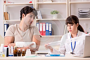 Young man with bandaged arm visiting female doctor traumatologis