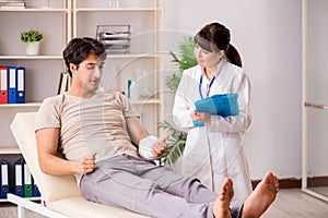 Young man with bandaged arm visiting female doctor traumatologis