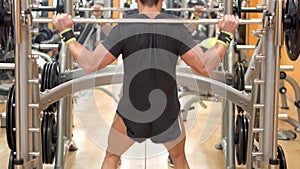 Young man with barbell doing squats in gym, sport, bodybuilding, lifestyle and people concept.