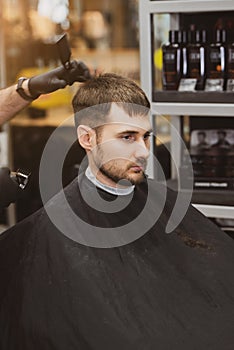 A young man in a Barber shop. Trendy guy with dark hair.