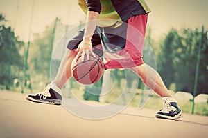 Young man on basketball court dribbling with ball. Vintage