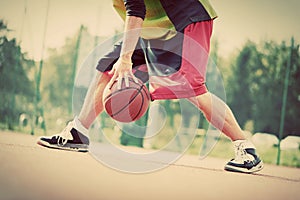 Young man on basketball court dribbling with ball. Vintage photo