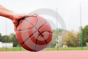 Young man on basketball court. Sitting and dribbling with ball