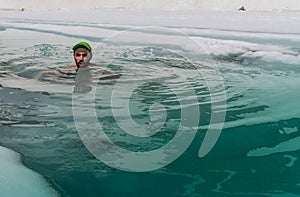 Young man bathing in the ice hole