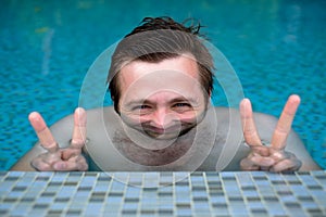 A young man is bathing in the pool and resting during the vacation. His face is distorted because of the water.