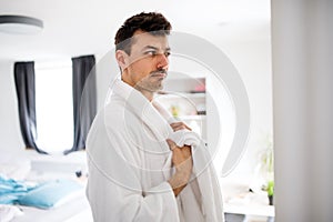 Young man with bathrobe in the bedroom, a morning routine.