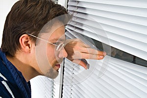 Young man in bathrobe looking out of the window