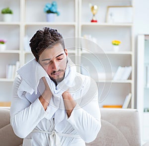 Young man in a bathrobe after shower drying hair with a towel