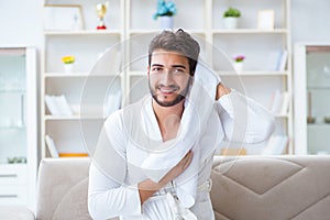 The young man in a bathrobe after shower drying hair with a towel