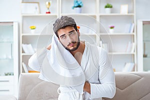 The young man in a bathrobe after shower drying hair with a towel