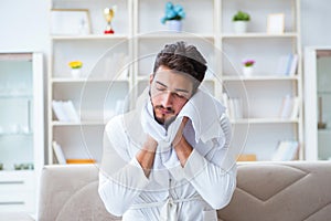 The young man in a bathrobe after shower drying hair with a towel